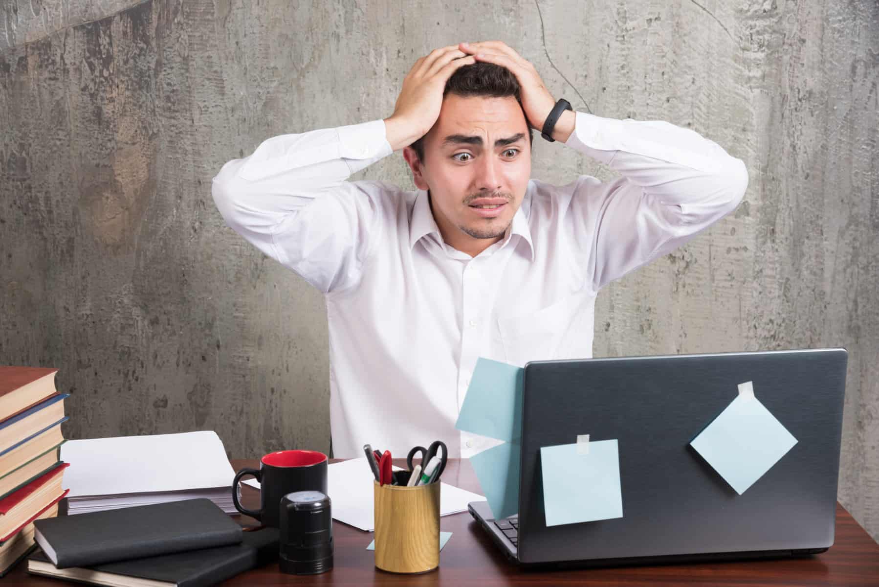 A man wearing a polo looks frustrated while staring at his laptop.