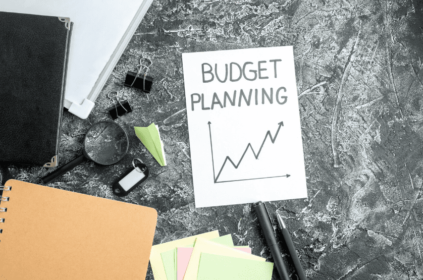 The words Budget Planning with an upward arrow on a piece of paper.