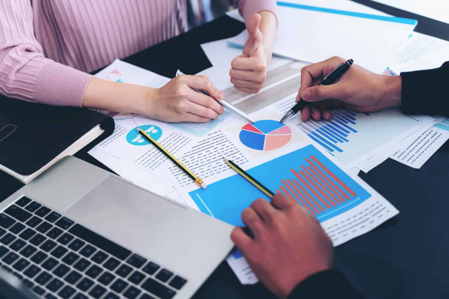 Hands pointing to charts on a table