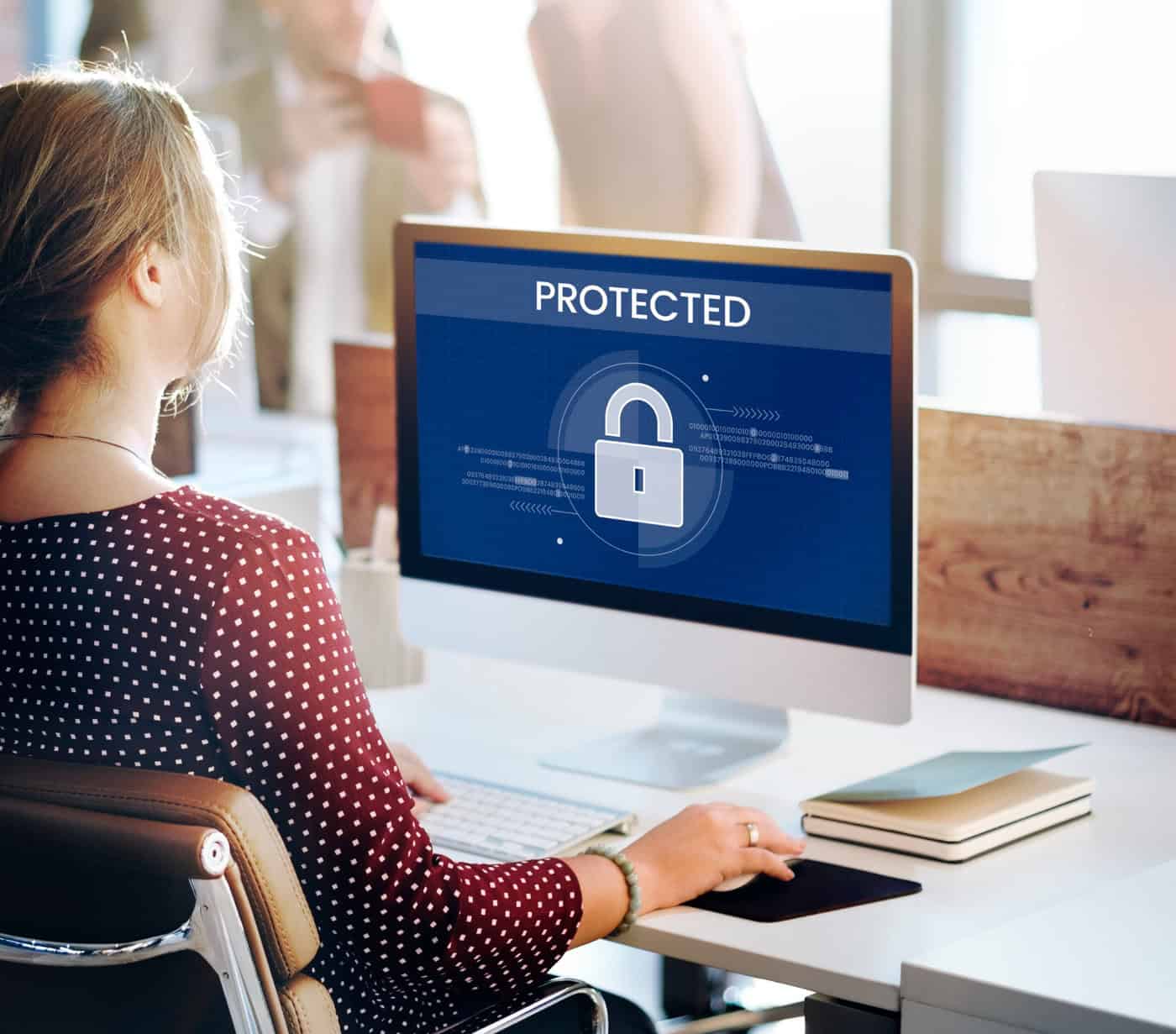 Woman in front of a computer with the word Protected on it.
