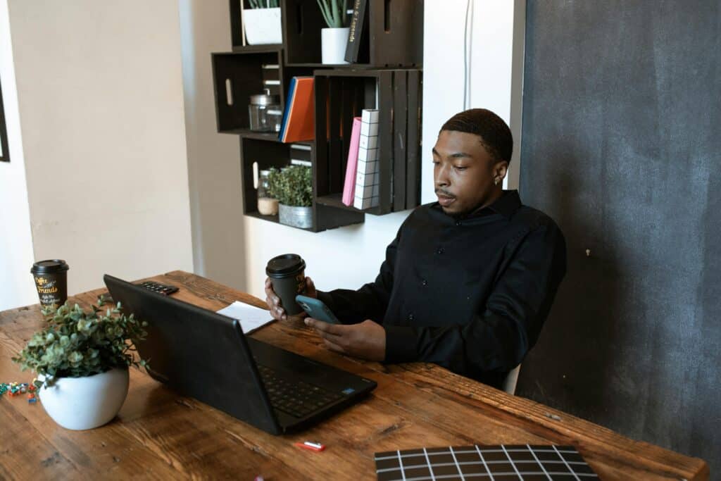 Man in Black Dress Shirt Sitting on Chair in Front of Laptop Computer