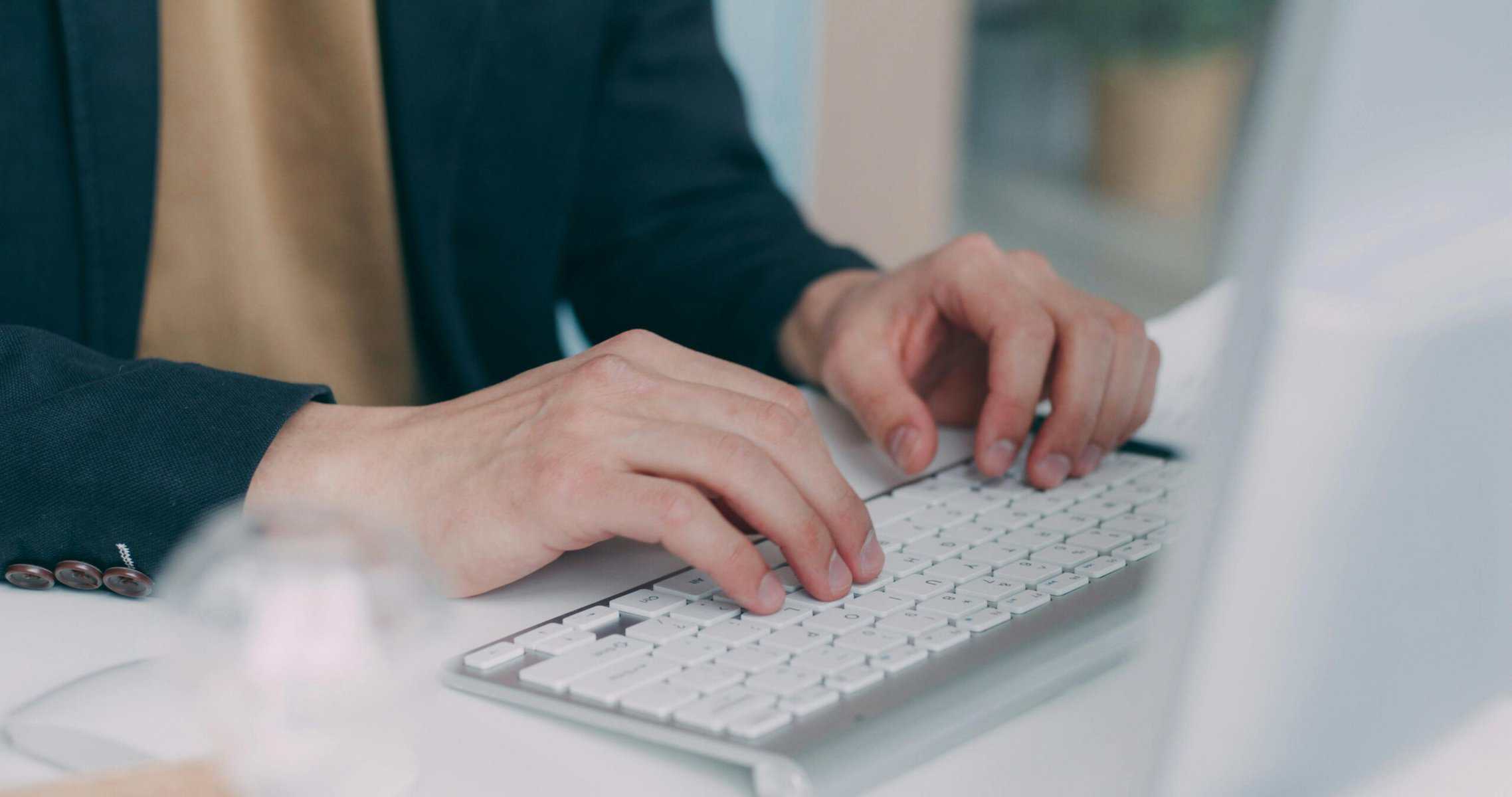 Fractional CFO hands typing on white keyboard